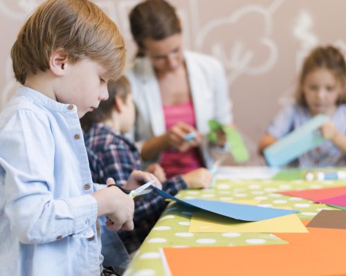 Program wychowawczo profilaktyczny przedszkola podczas zajęć, dziecko wycinające wzorki w papierze.
